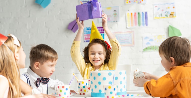 Kinder mit Papierkronen und Geschenken bei einer Feier