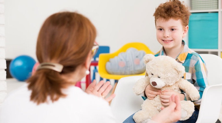 Kind mit Teddybär im Gespräch mit einer Fachkraft