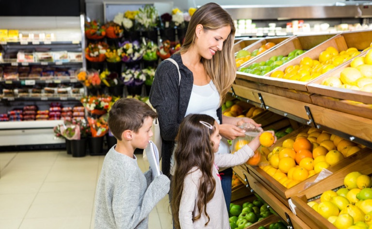 Mutter mit zwei Kindern im Supermarkt vor der Obstauslage
