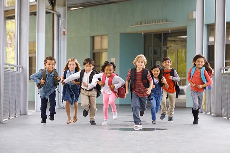 Kinder mit Schulranzen rennen aus dem Schulgebäude