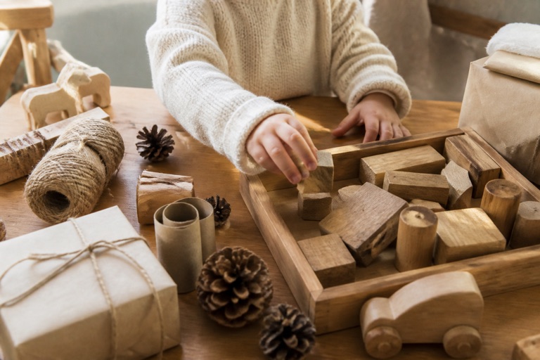 Holzspielzeug und Bastelmaterial auf einem Tisch mit schlichtem Packpapier