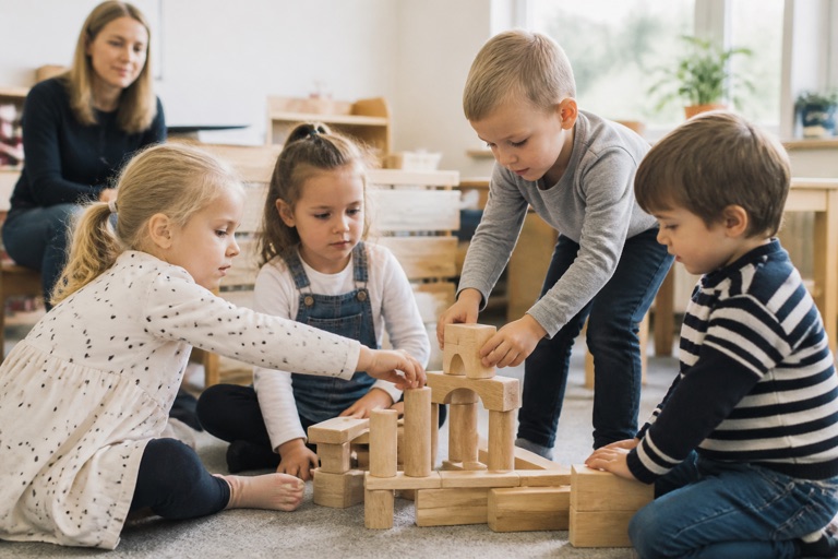 Kinder lösen gemeinsam eine Bauaufgabe mit Holzklötzen