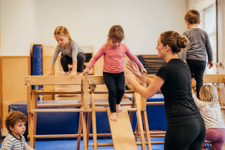Kinder klettern und balancieren an einem Holzgerüst in der Turnhalle