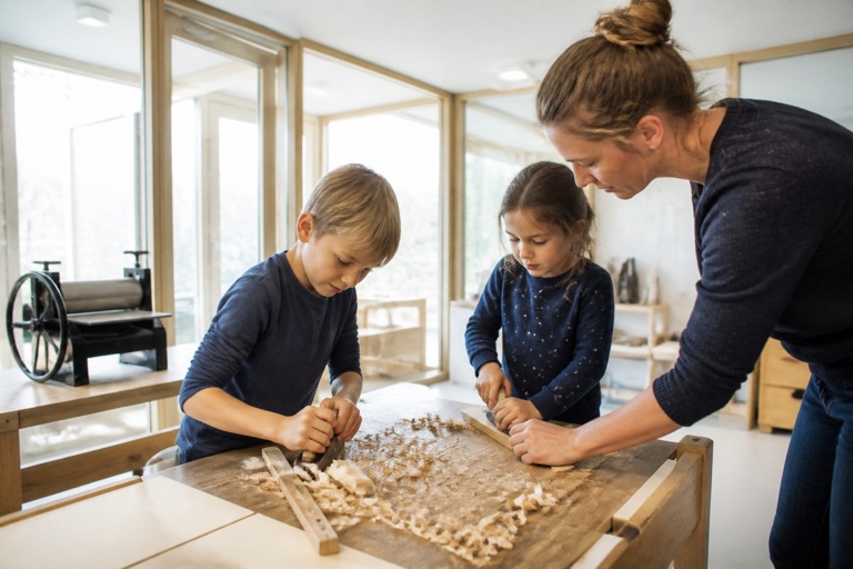 Kinder arbeiten mit echtem Werkzeug an einer Werkbank