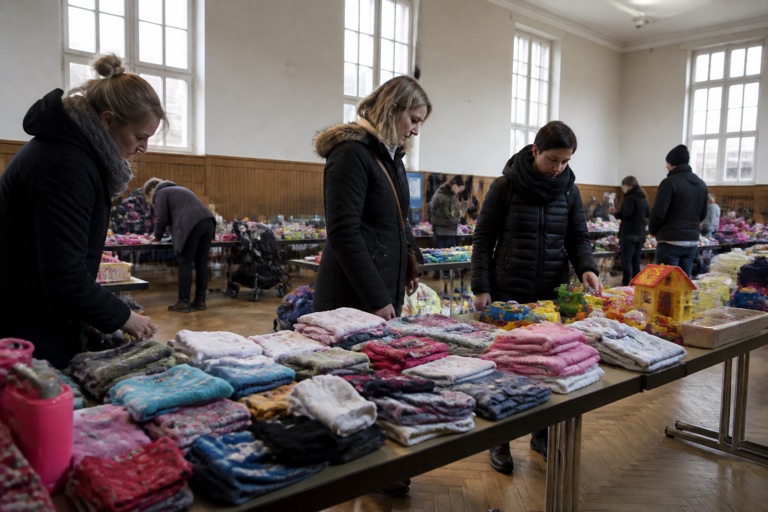 Kinderflohmarkt in einer Halle: Tische mit Kleidung und Spielzeug