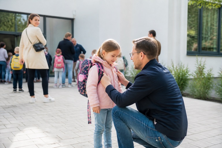 Vater bringt sein Kind morgens zum Eingang des Kindergartens