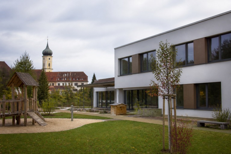 Aussenansicht eines städtischen Kindergartens mit Spielplatz