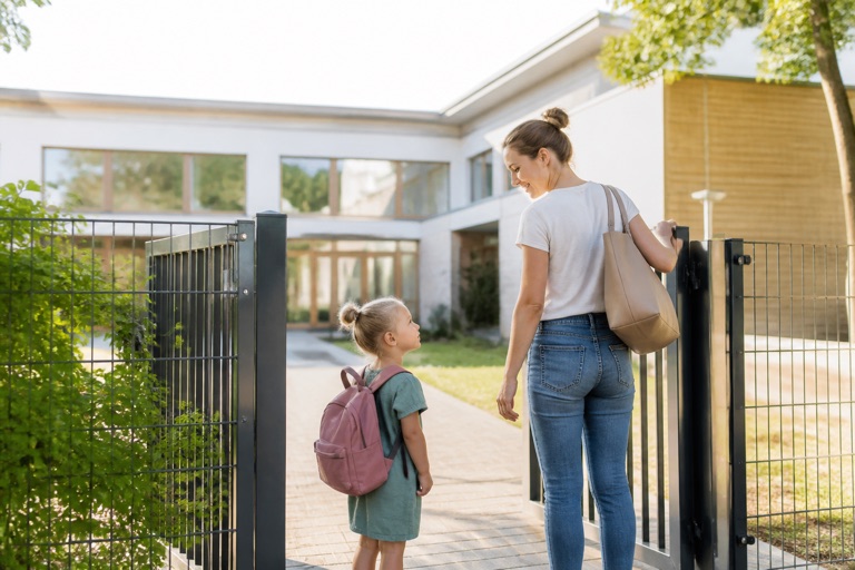 Mutter und Kind mit Rucksack am Eingang eines Kindergartens